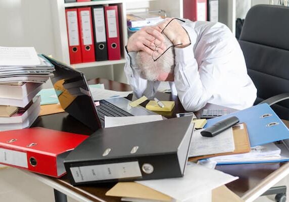 Man sitting at cluttered desk in need of workspace cleaning